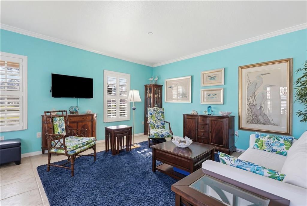 Living area with crown molding, plantation shutters and low maintenance tile floors
