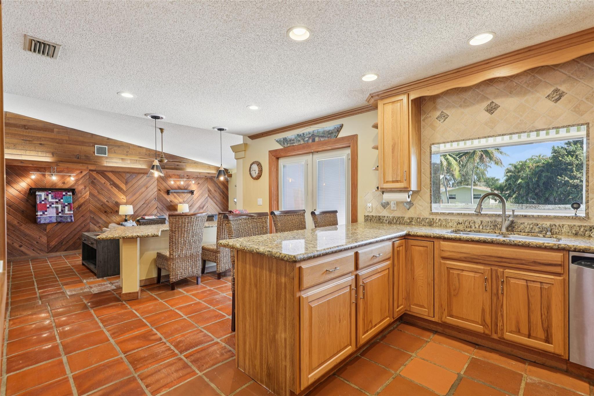 Granite countertops and bar for extra seating or work included, acting as a perfect bridge between the kitchen and living room.