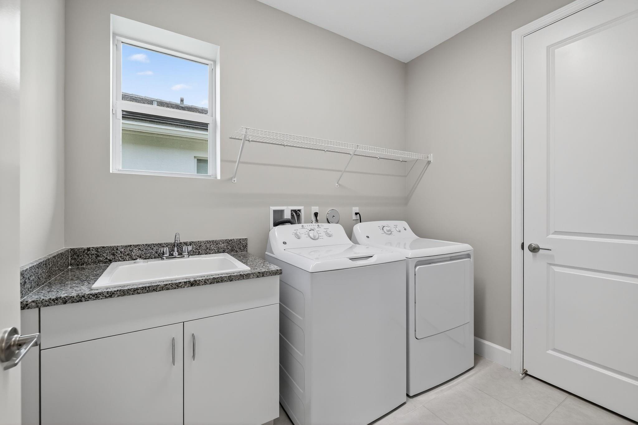 Laundry room showing upgraded sink with cabinet.