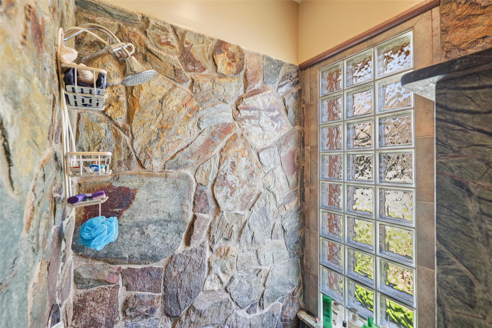 Roomy primary bathroom including beautiful natural rock feature in step-down shower.