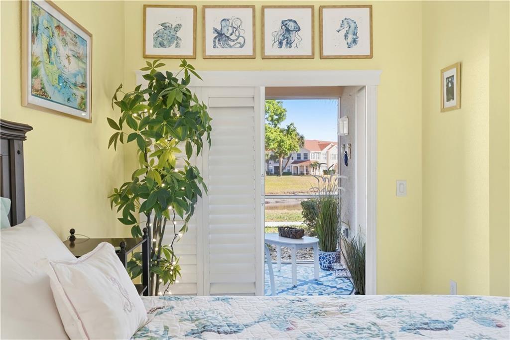 Bedroom featuring access to exterior and views of pond and clubhouse.