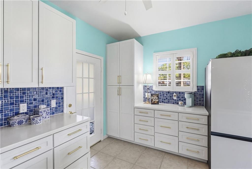 Kitchen featuring freestanding refrigerator, white cabinetry, a ceiling fan, and light tile patterned floors
