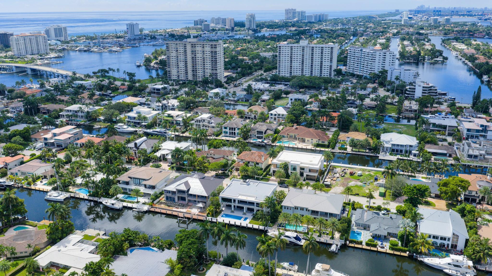 A vibrant neighborhood scene showing waterfront homes leading toward the Fort Lauderdale coastline and ocean horizon.