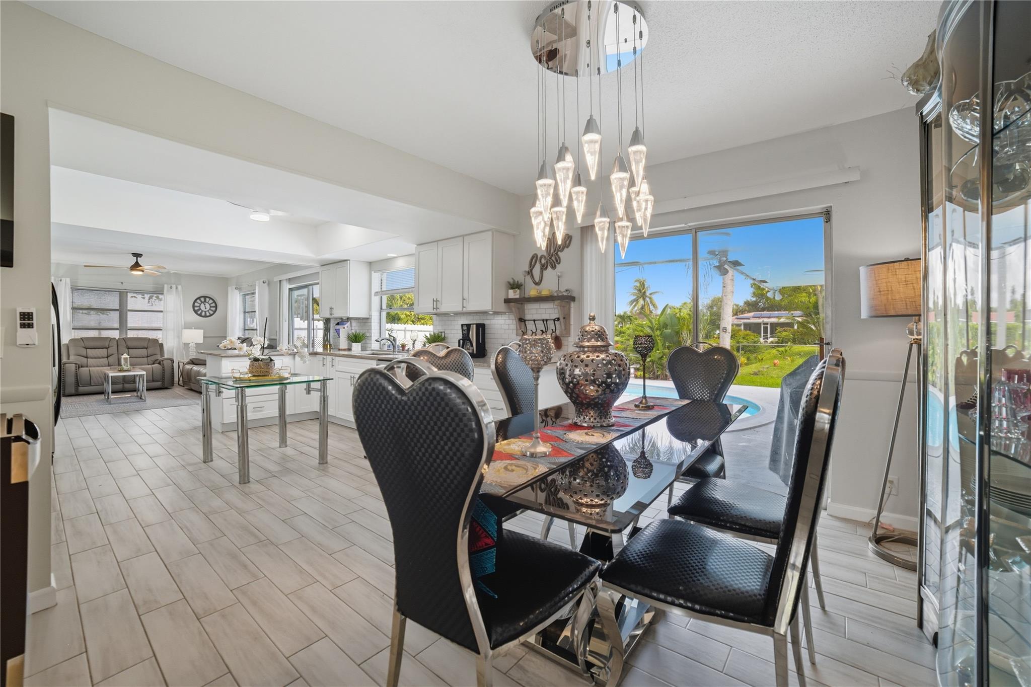 Dining room is open to kitchen, family room and living room area. Tile plank floors. Designer chandelier