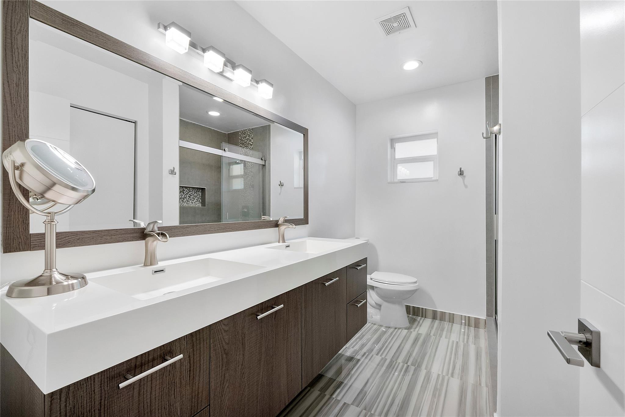 The master bathroom has double vanities and porcelain flooring in stylish neutral colors