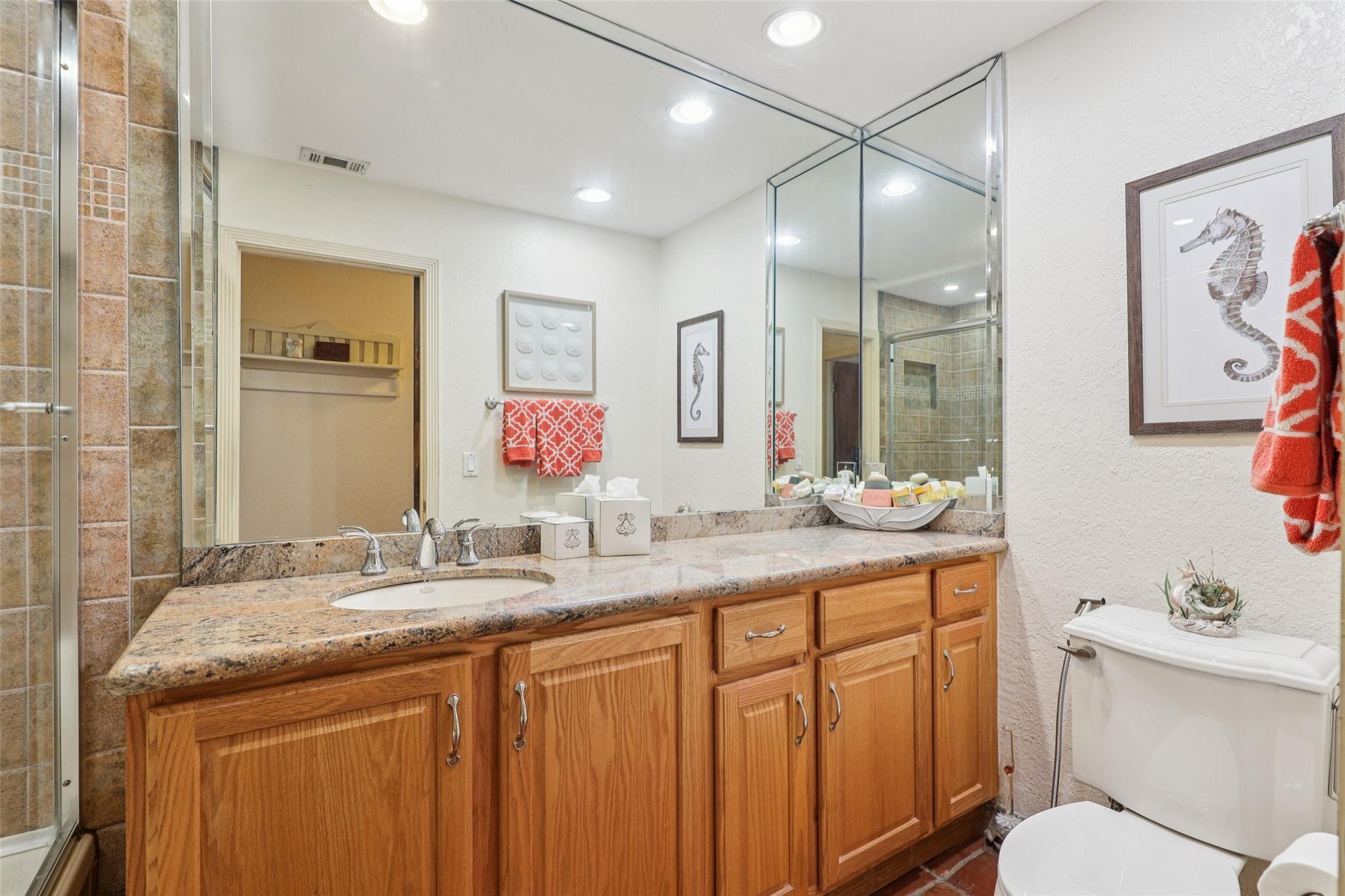 Comfortably sized guest bathroom with shower/tub combination and long granite countertop.