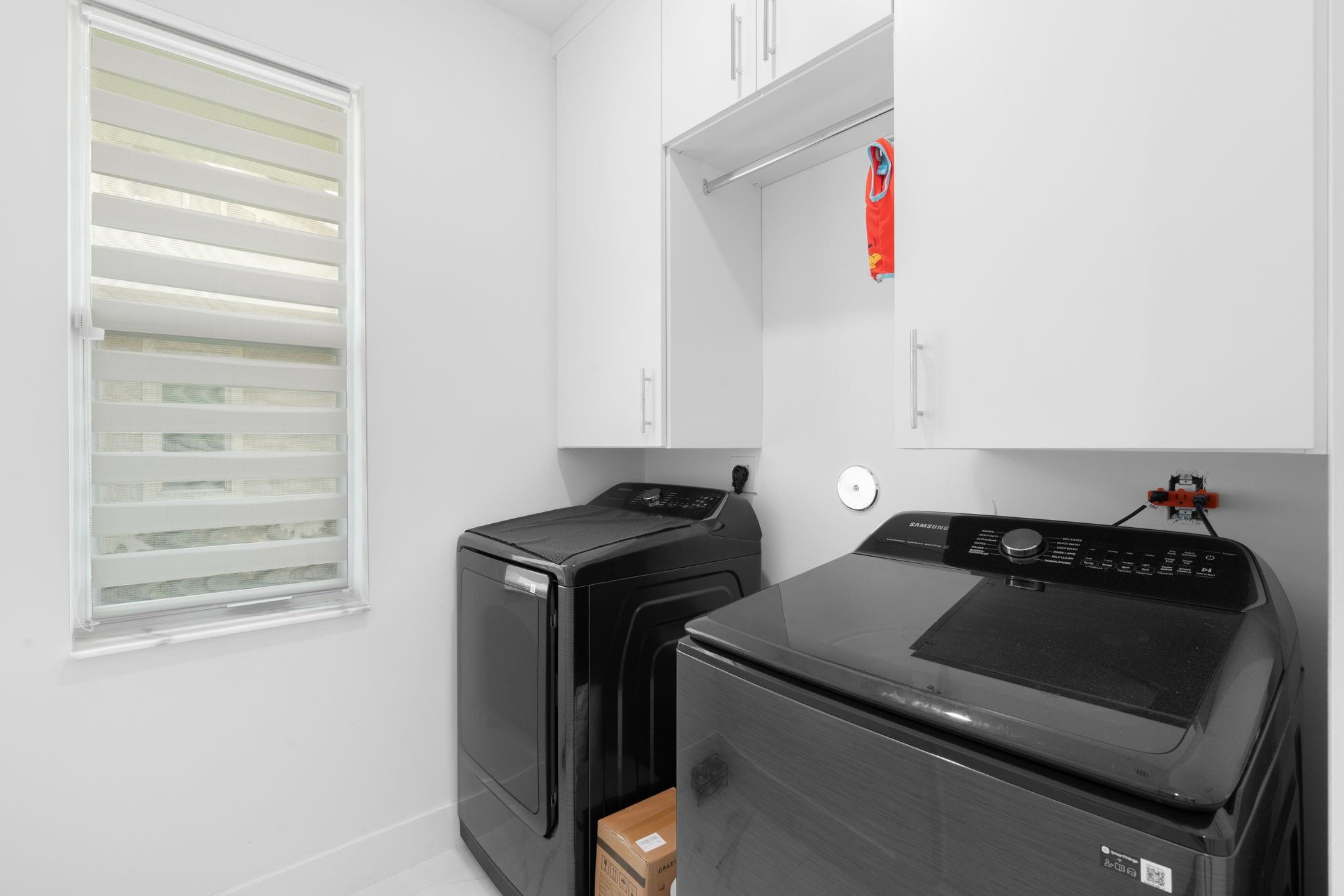 First Floor Washer and Dryer with built in Cabinets and a Window with Modern Roller Shade.