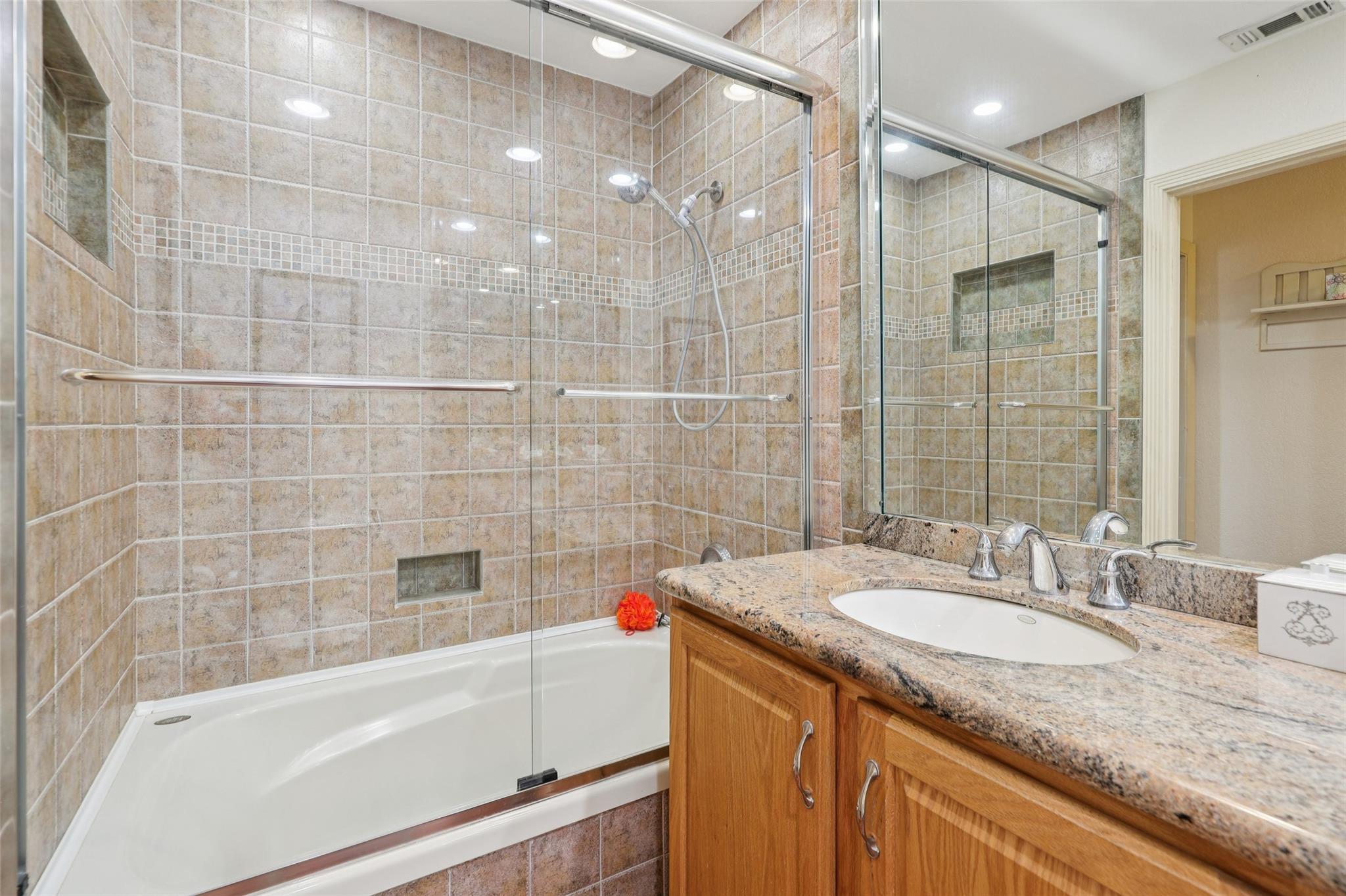 Comfortably sized guest bathroom with shower/tub combination and long granite countertop.