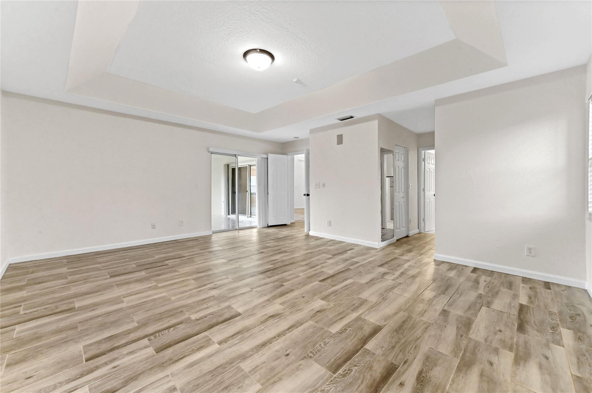 Primary bedroom with two (2) walk-in closets and sliding glass door to patio