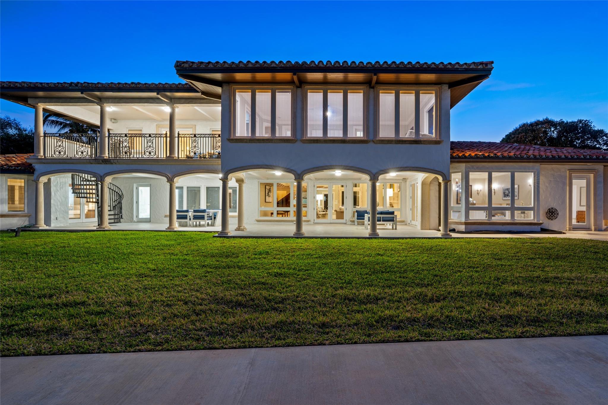A captivating twilight poolscape featuring an inviting resort-style pool, spa, and elegant lounge areas overlooking the water. Warmly illuminated and impeccably designed, this outdoor sanctuary is perfect for unforgettable evenings under the coastal sky.