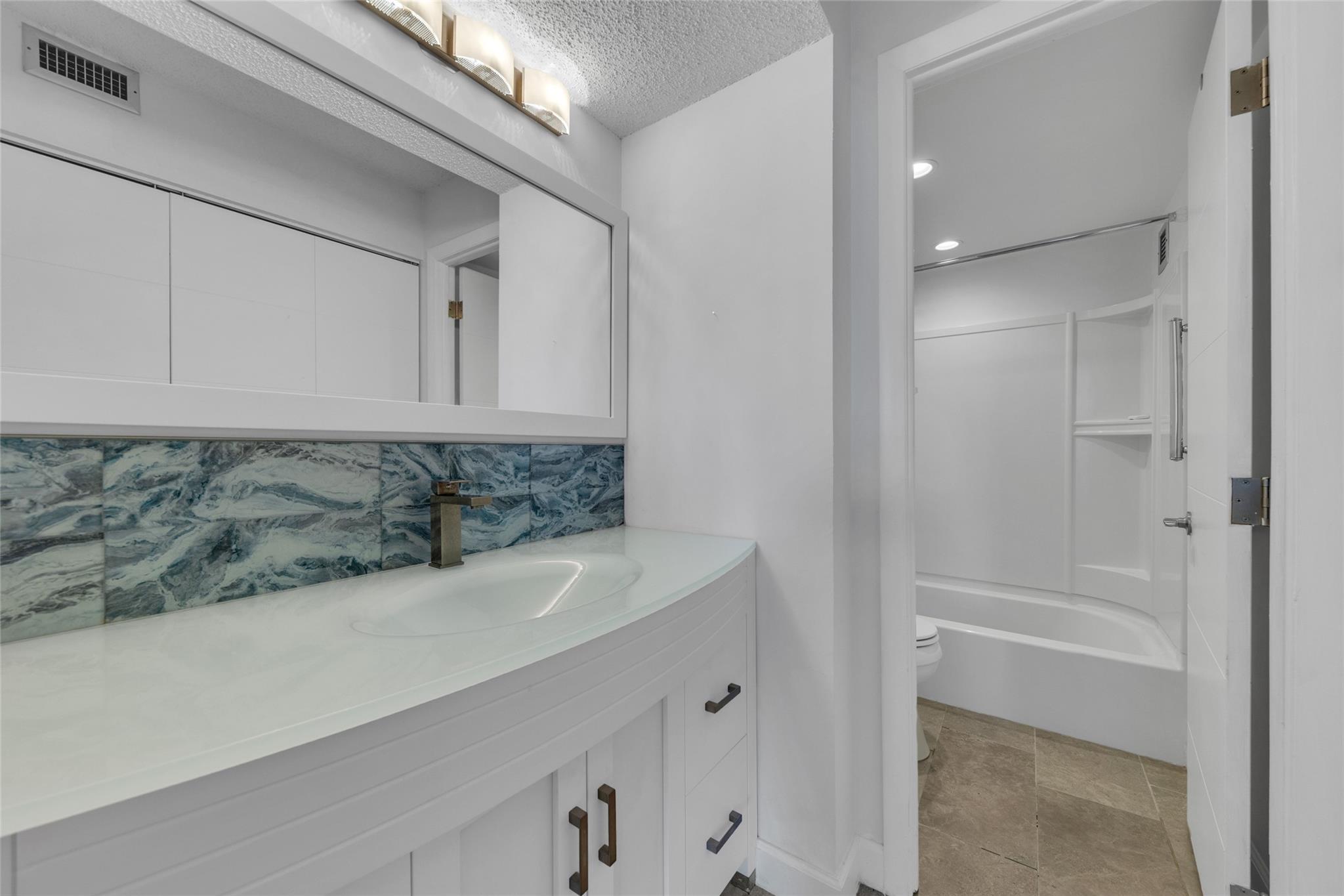 Beautifully remodeled Vanity and Dressing Area with combination tub and shower in view.