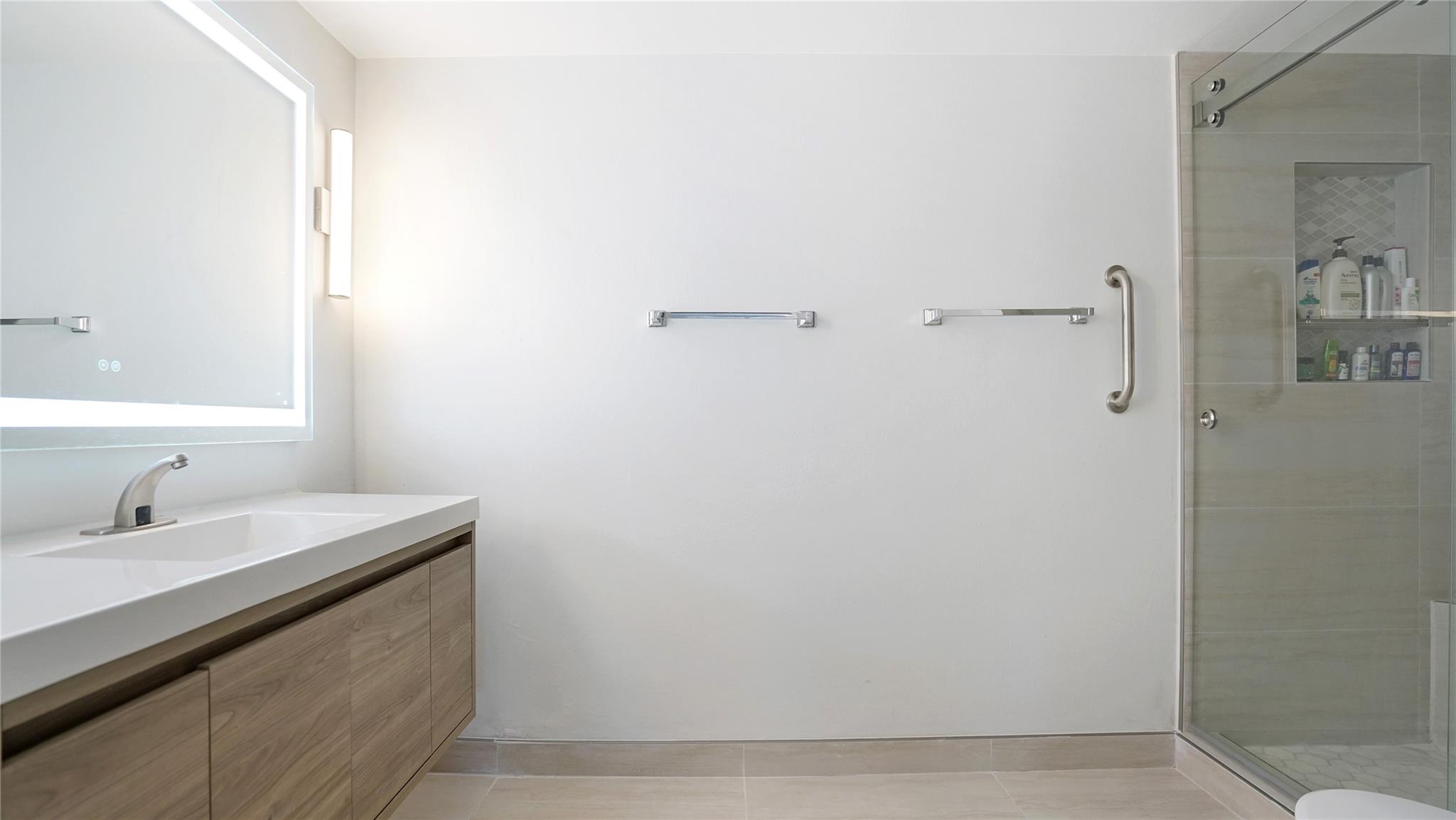 The renovated primary bathroom features a quartz topped floating vanity.