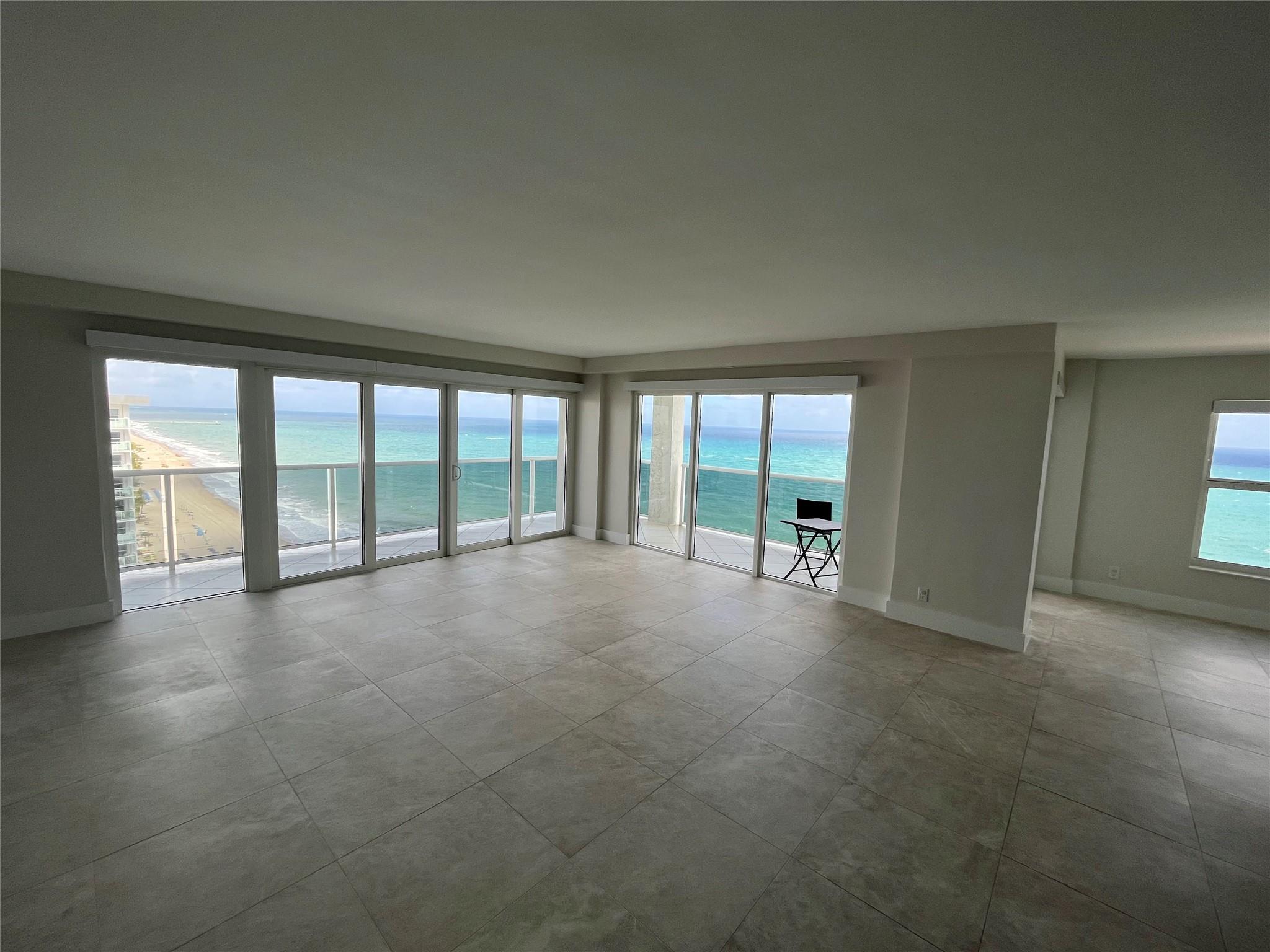 The large living room with marble tile and floor-to-ceiling impact windows and doors.