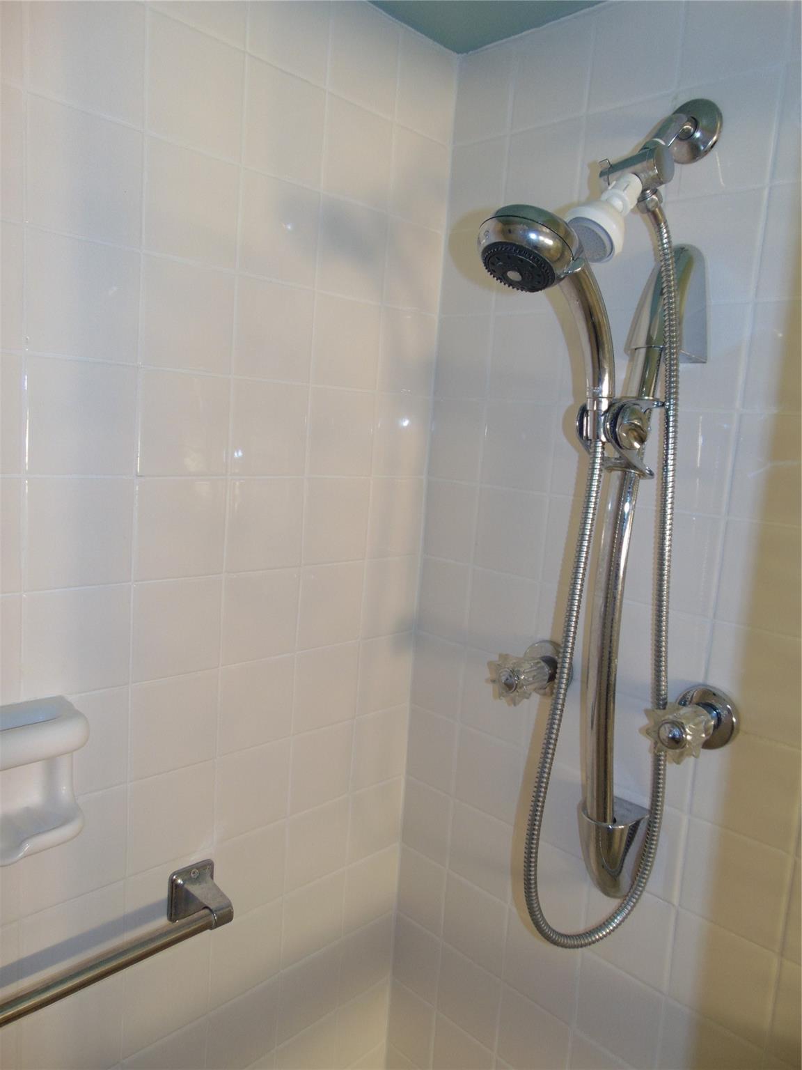 STALL SHOWER AT GUEST BATH WITH UPGRADED DOUBLE SHOWER HEADS WITH VERTICAL ADJUSTABLITY. ALL WHITE TILE AT GUEST BATH.