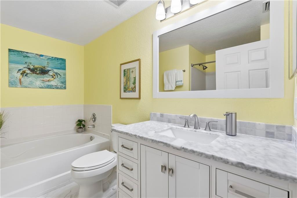 Ensuite primary bathroom featuring undermount vanity sink, separate stall shower and garden tub