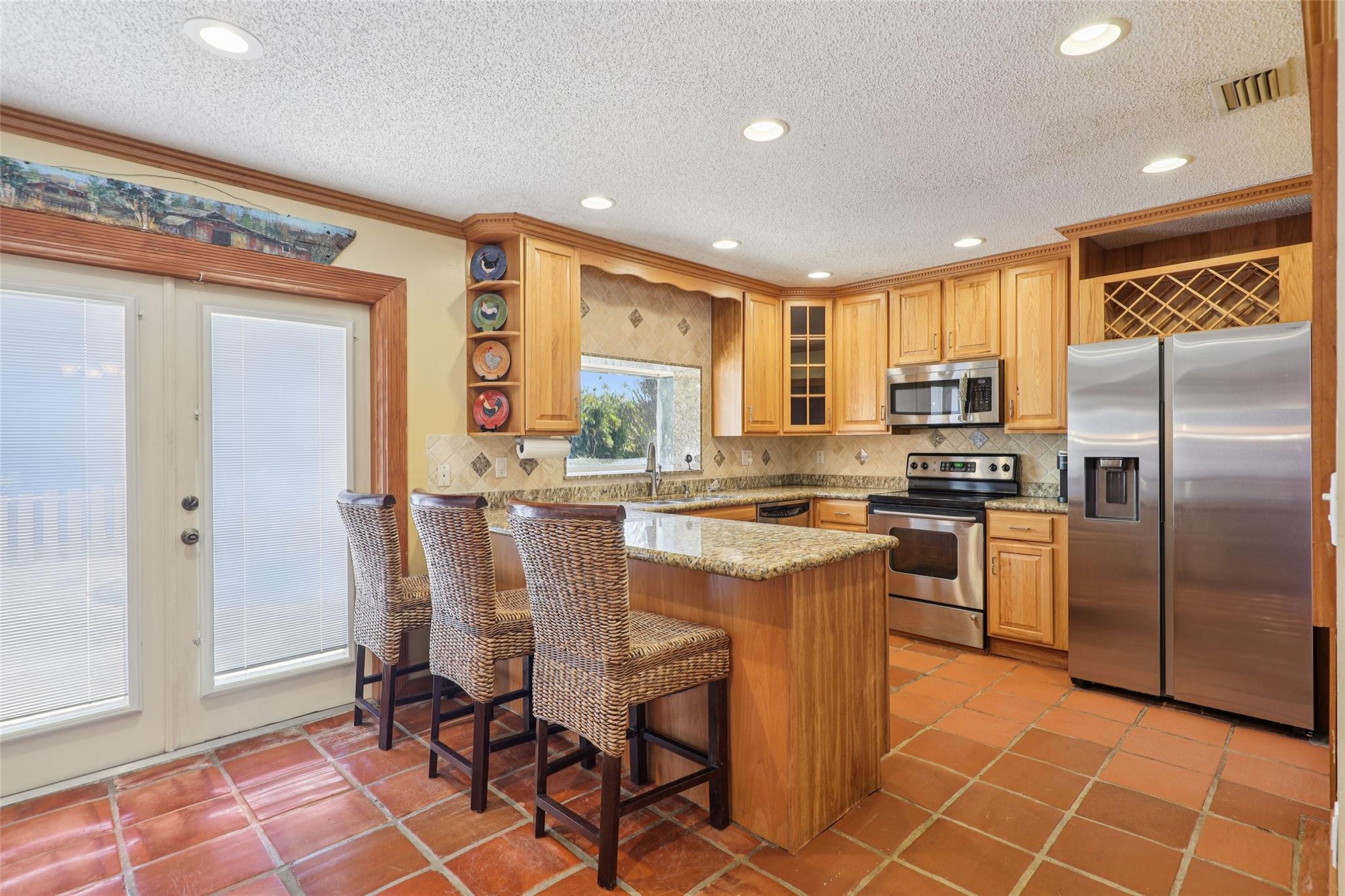 Granite countertops and bar for extra seating or work included, acting as a perfect bridge between the kitchen and living room.