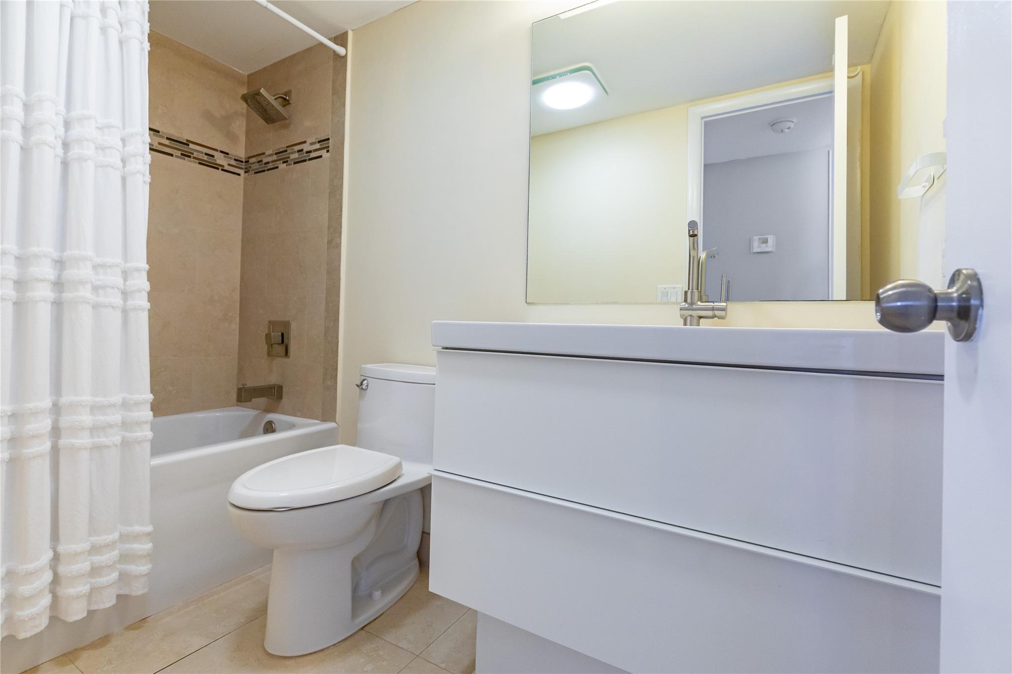 Guest bathroom with modern vanity and tiled shower/tub area.