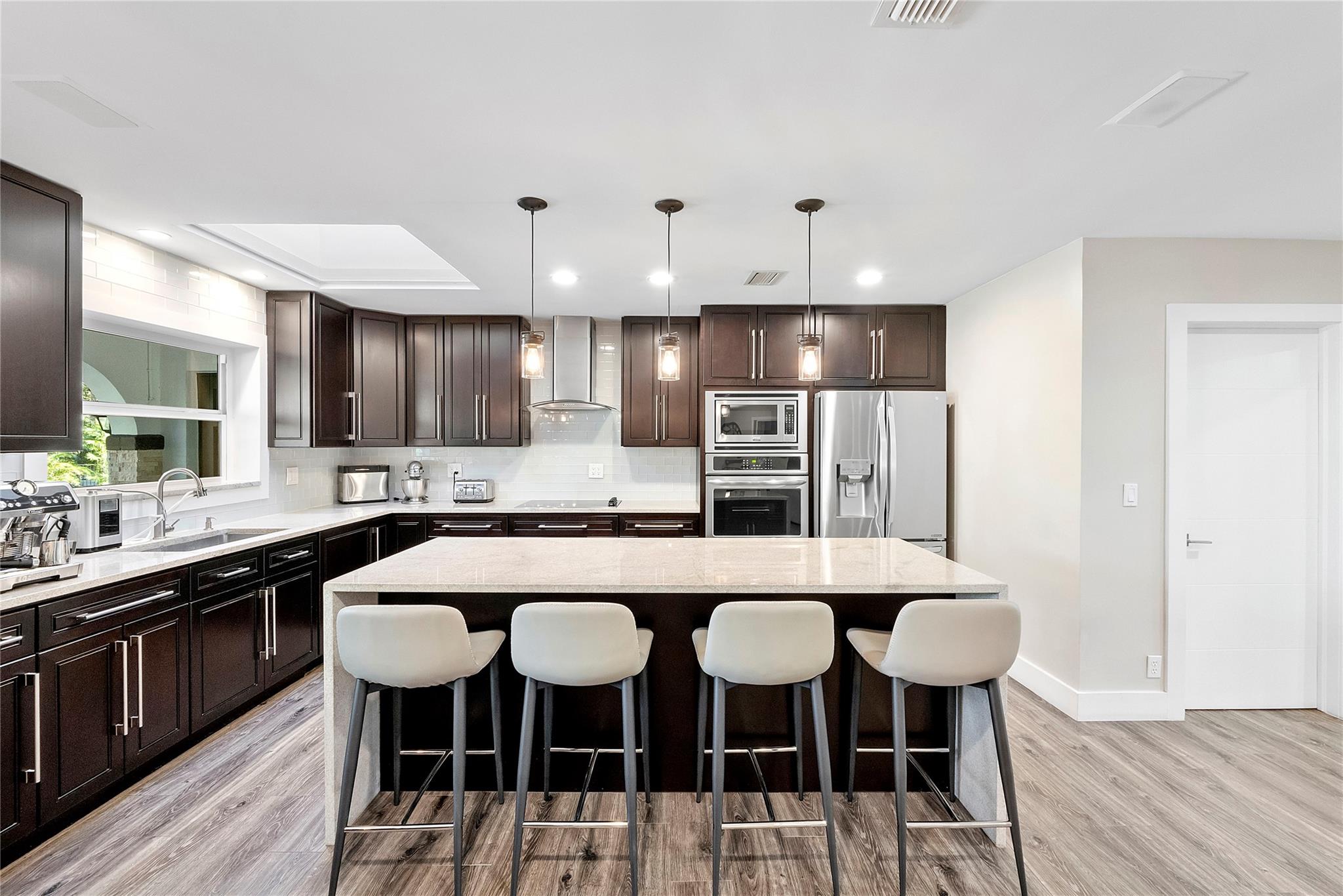 Granite countertops with a waterfall drop on both sides, Subway backsplash with stainless gourmet hood,