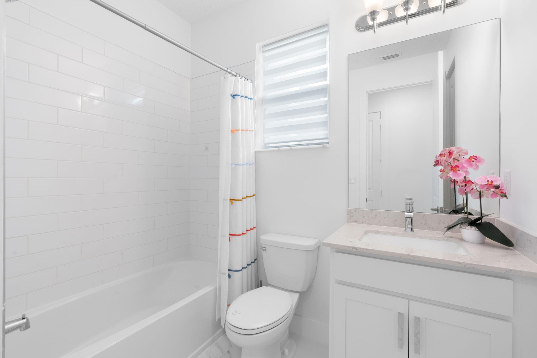 First Floor 2nd Bath with Modern Subway Tile and Continuous Flooring Throughout the First Floor. Quartz Counter Vanity with Porcelain Sink.