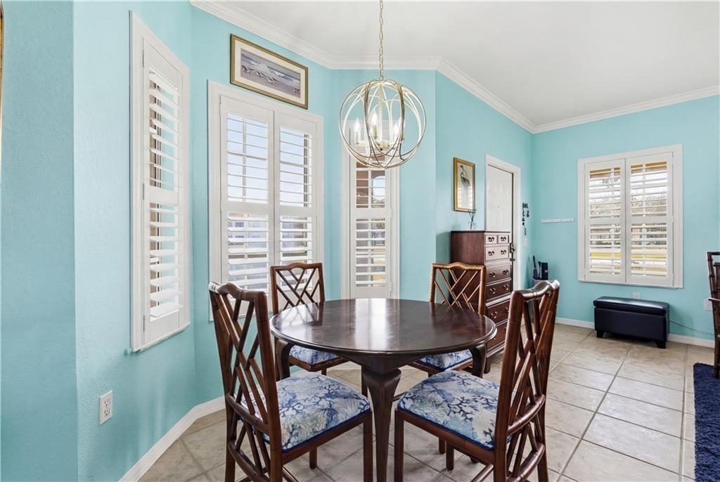 Dining room with crown molding, custom lighting, and light tile patterned floors