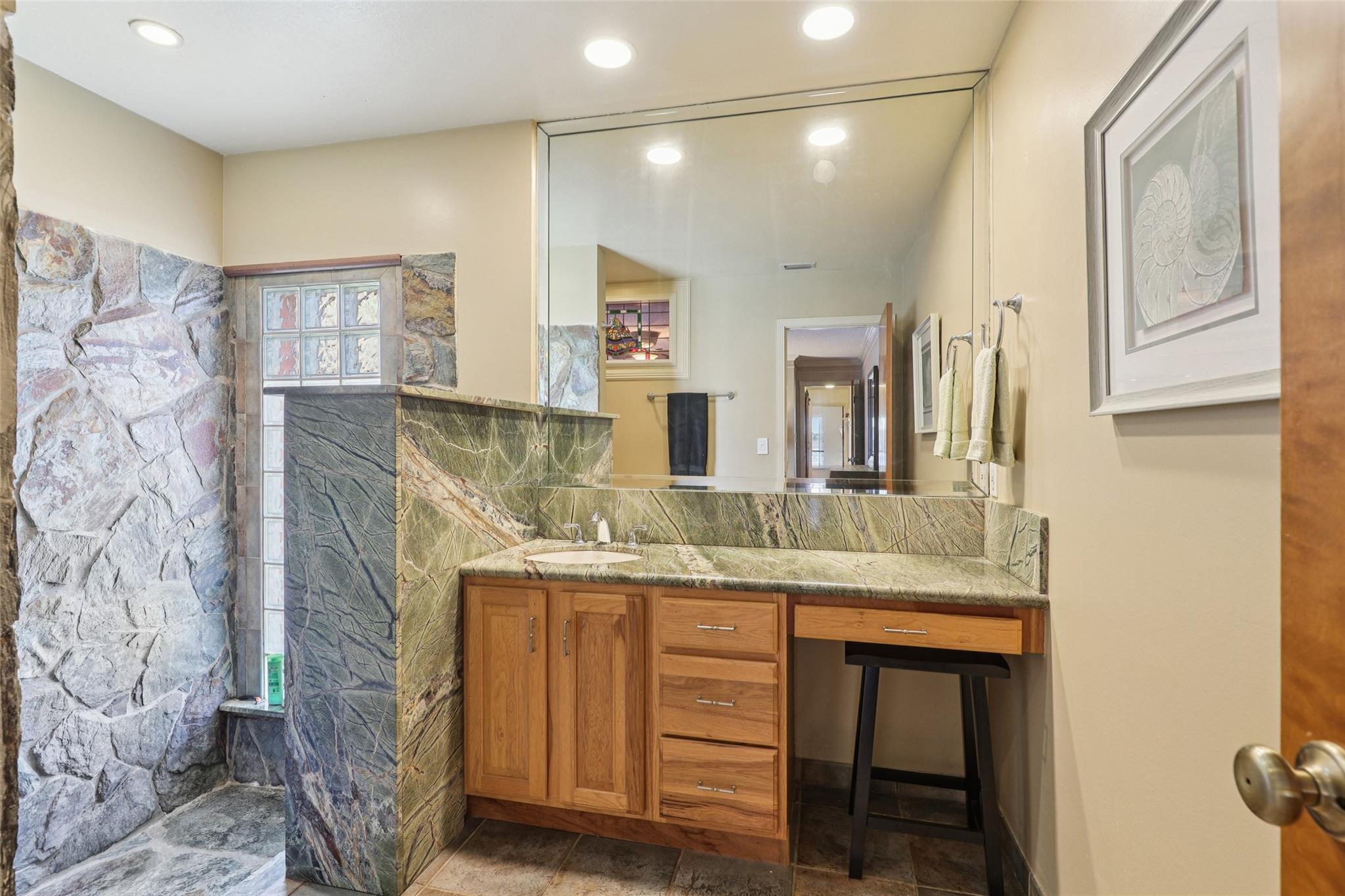 Roomy primary bathroom including beautiful natural rock feature in step-down shower.