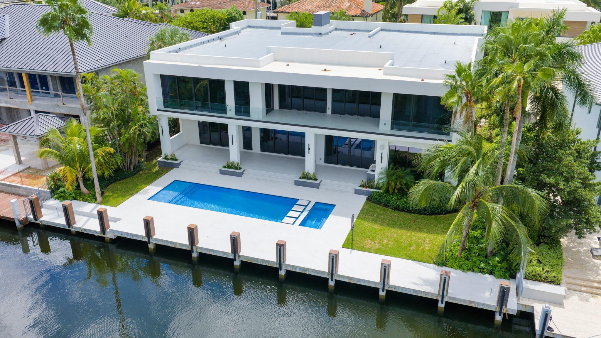 A focused aerial of a modern residence with a resort-style pool and dock directly on the canal.
