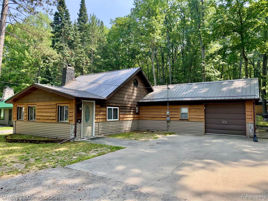 Chalet / cabin featuring a metal roof, asphalt driveway, and a chimney