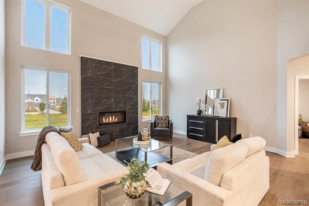 Living room with wood finished floors, a premium fireplace, and high vaulted ceiling