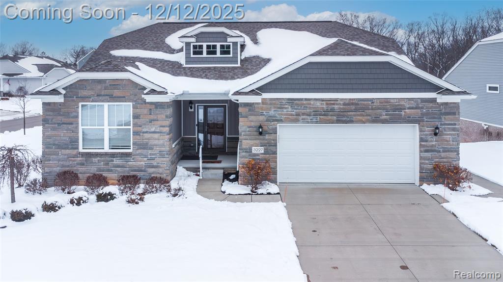 View of front of home with stone siding, an attached garage, and concrete driveway