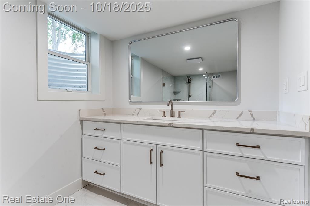 Full bathroom featuring vanity, a stall shower, and light marble finish flooring
