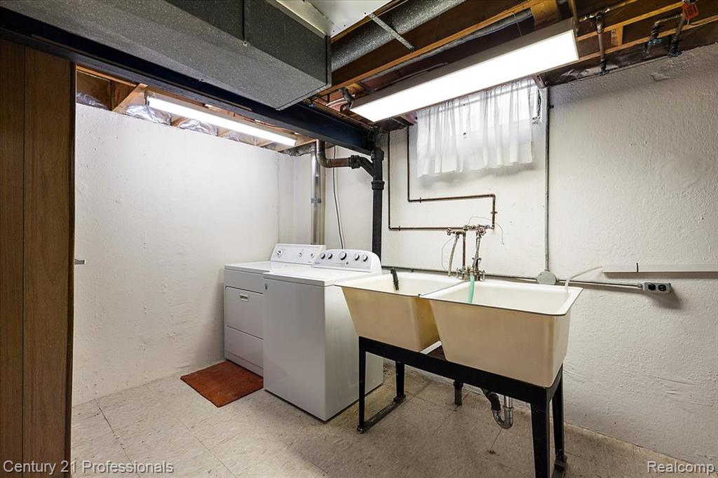 Laundry room featuring tile patterned floors, a textured wall, and separate washer and dryer
