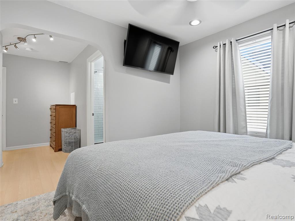 Bedroom featuring wood finished floors and arched walkways