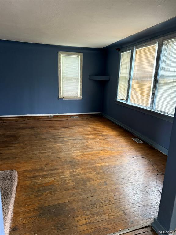 Spare room featuring plenty of natural light and dark wood finished floors