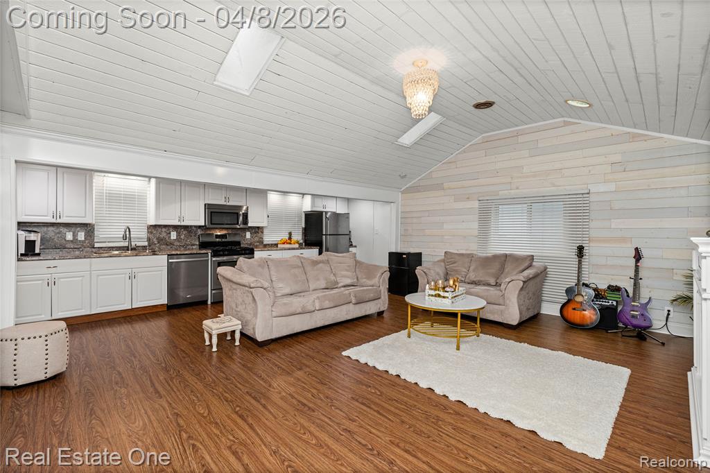 Living area featuring wooden walls, dark wood finished floors, and a skylight