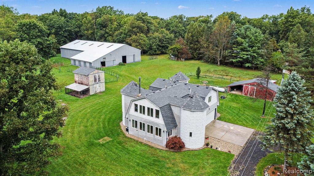 Architectural residence featuring a turretted exterior, expansive green lawn, substantial barn structure, detached storage building, and a classic red barn