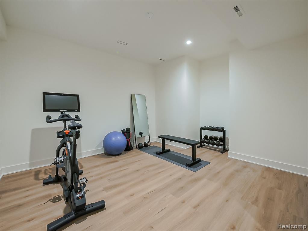 Exercise area with wood finished floors and recessed lighting