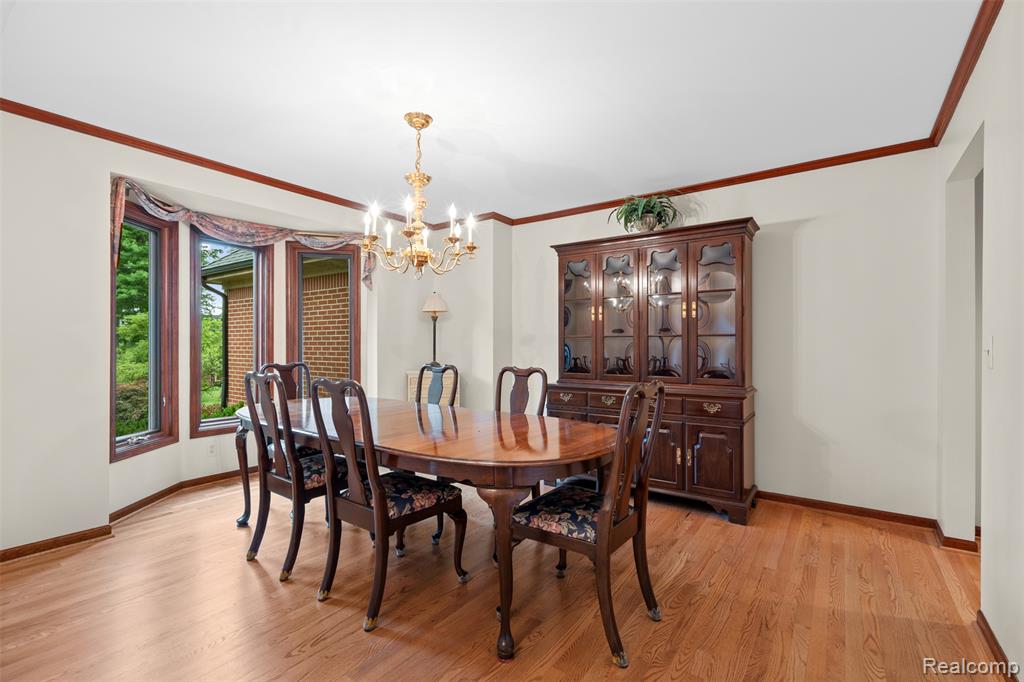 Dining space featuring ornamental molding, a chandelier, and light wood-style flooring