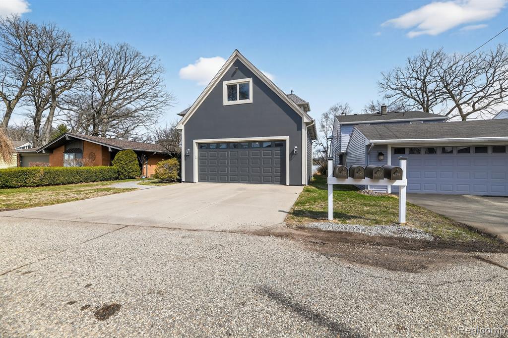 View of front of property featuring a garage, concrete driveway, and a front yard