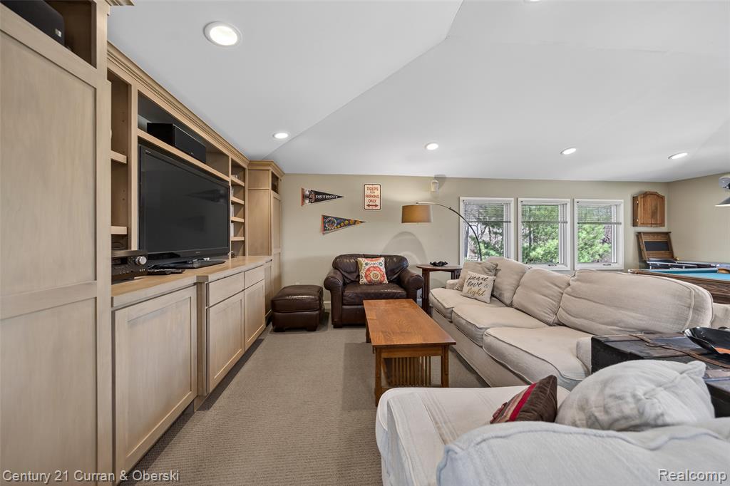 Living area featuring lofted ceiling, light colored carpet, and recessed lighting