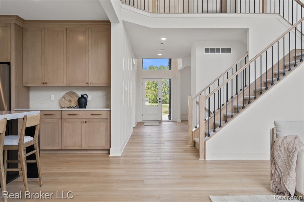 Corridor with stairs, light wood-style floors, arched walkways, and recessed lighting