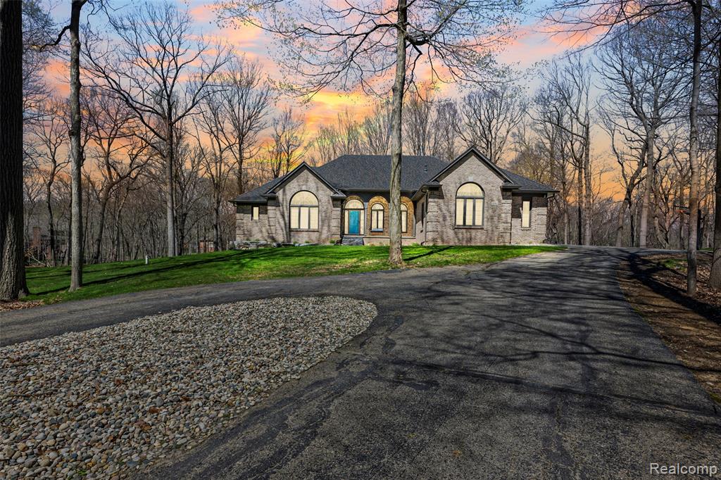 French country home featuring curved driveway, a lawn, and stone siding