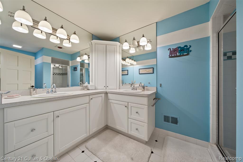 Bathroom featuring double vanity, a shower stall, and light tile patterned flooring