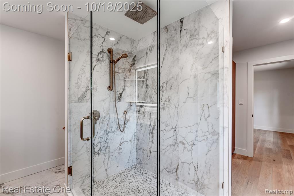Bathroom featuring a marble finish shower and light wood-style floors