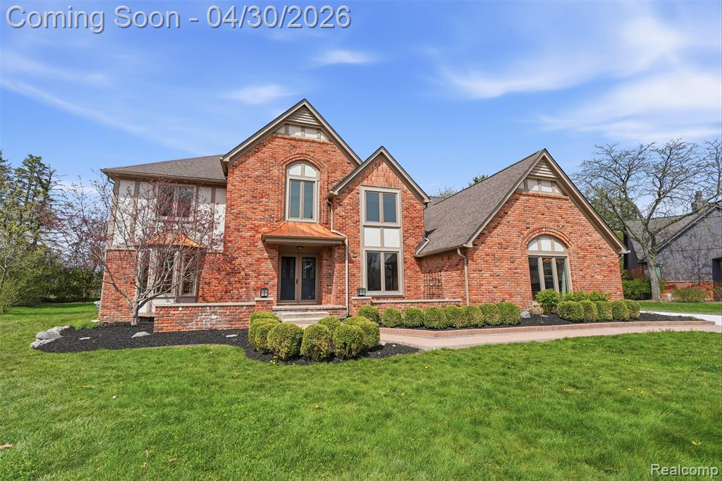 View of front of house featuring a front lawn and brick siding