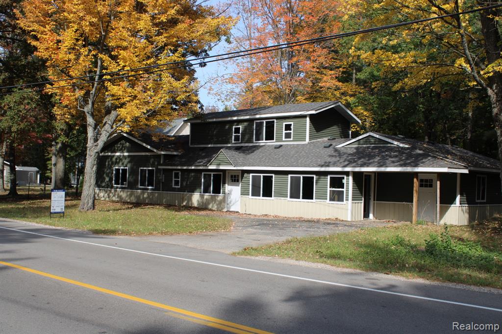 View of front of property featuring a shingled roof and view of scattered trees