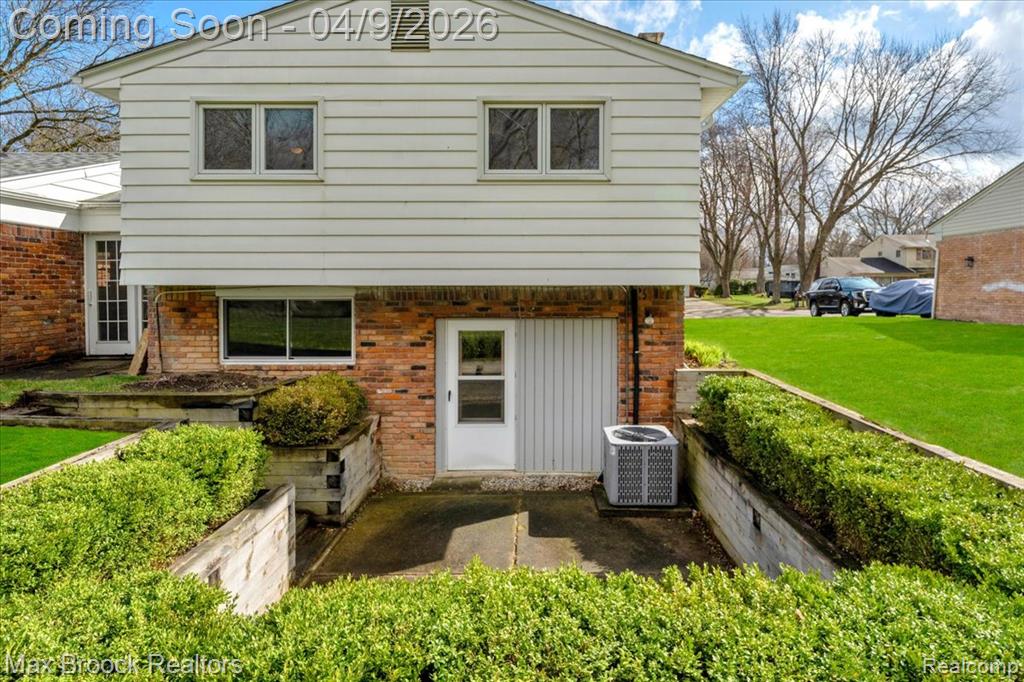Rear view of property featuring brick siding and a lawn