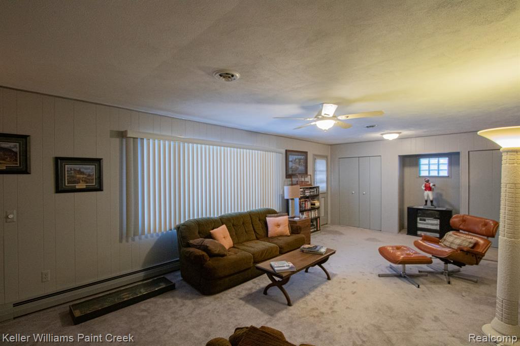 Living area with a baseboard radiator, carpet floors, a textured ceiling, and ceiling fan