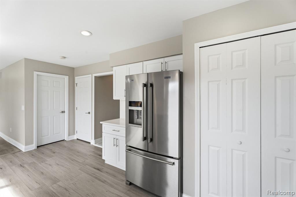 Kitchen with high end refrigerator, white cabinetry, light wood-style flooring, and recessed lighting