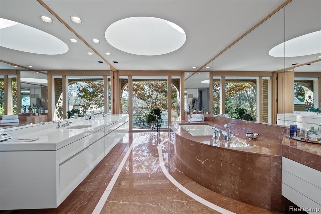 Bathroom featuring recessed lighting, marble tiled floors, a garden tub, and vanity