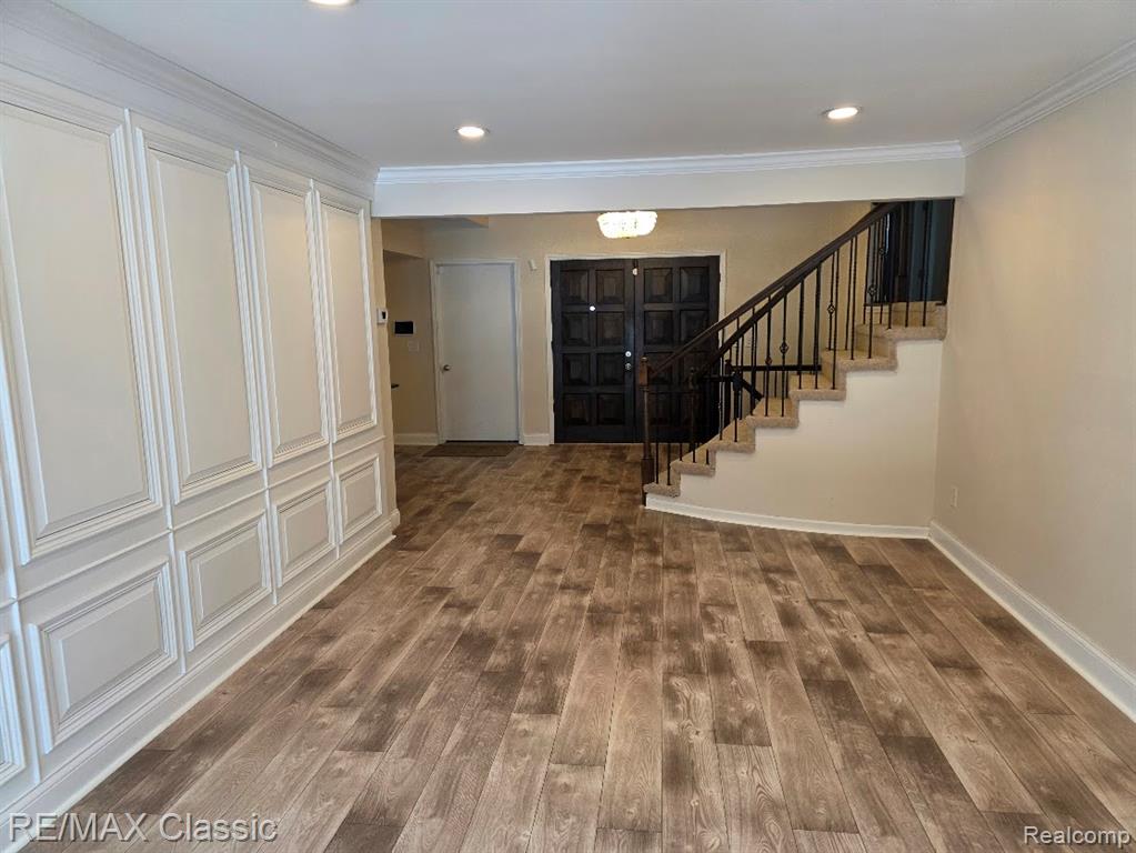 Entrance foyer with stairway, dark wood finished floors, crown molding, and recessed lighting